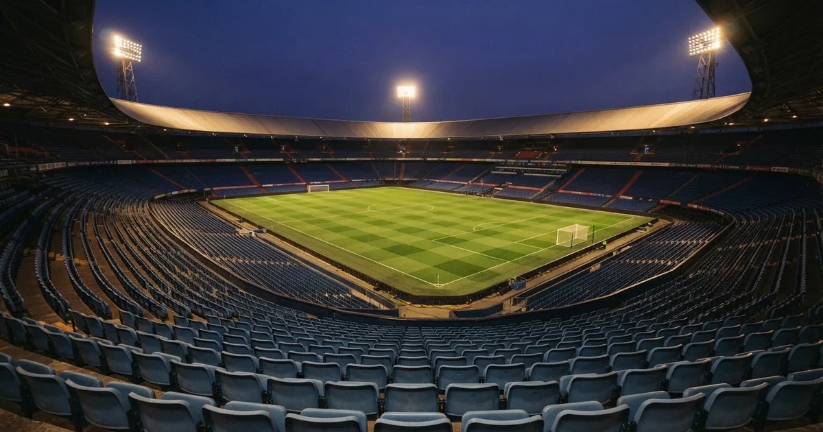 Leere Sitzreihen eines großen Stadions unter Flutlicht, dahinter die ferne Sicht auf den hell beleuchteten Rasen nach Sonnenuntergang.