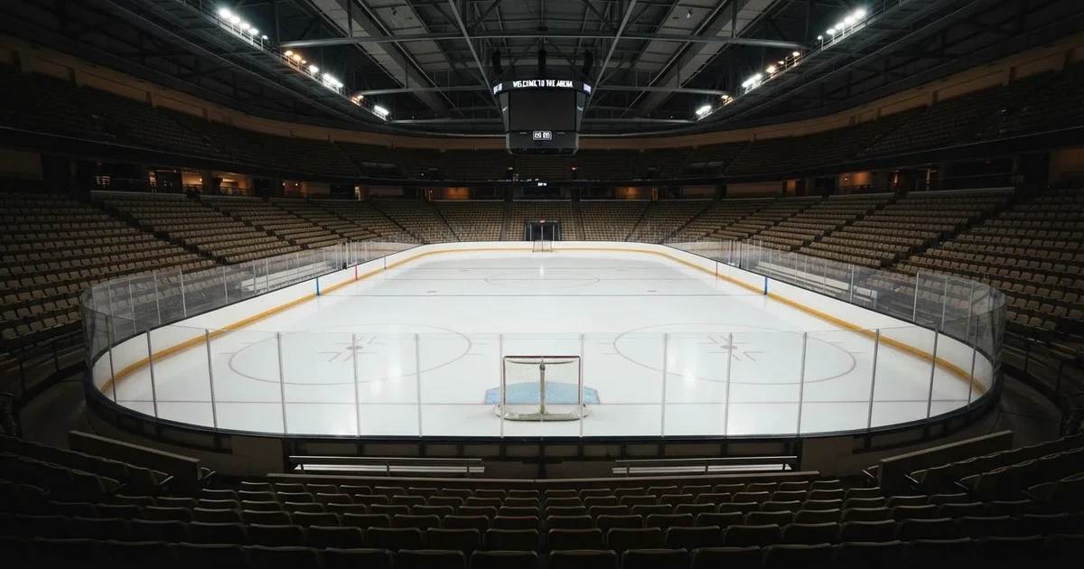 Eine Eishockeyhalle von der Tribüne aus gesehen, spiegelglatte Eisfläche, Banden ohne Schriftzüge, helles Flutlicht.