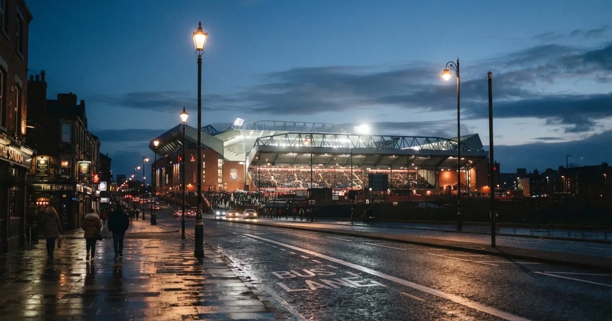 Ein großes Fußballstadion mit hell erleuchtetem Rund, aus der Ferne am Abend gesehen, davor eine breite Allee mit Laternen.