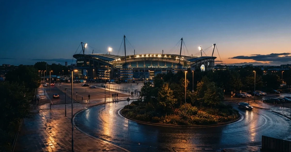 Ein Fußballstadion in der Dämmerung aus der Ferne, die Flutlichter gerade eingeschaltet, davor ein Kreisverkehr mit Laternen.