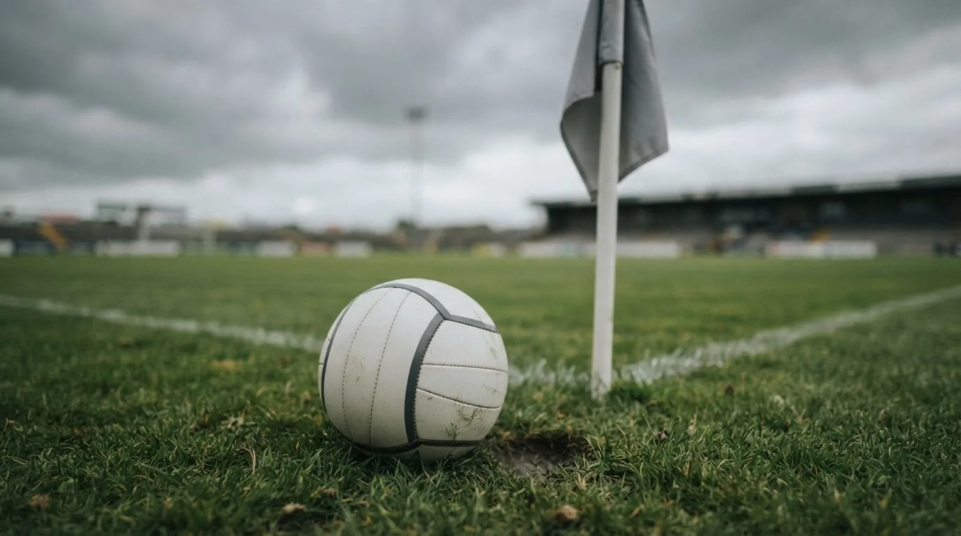 Ein Fußball liegt neben einer Eckfahne auf kurz gemähtem Rasen unter bewölktem Himmel.
